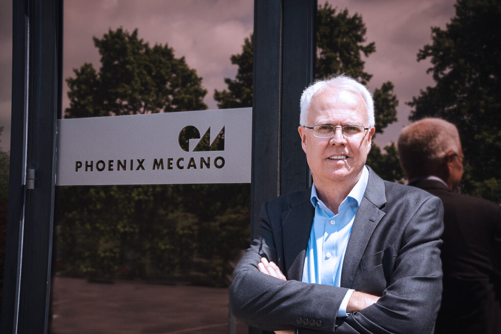 Dr. Phillip Brown posing by Phoenix Mecano sign